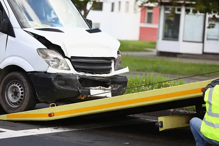 Damaged white van loading onto a trailer