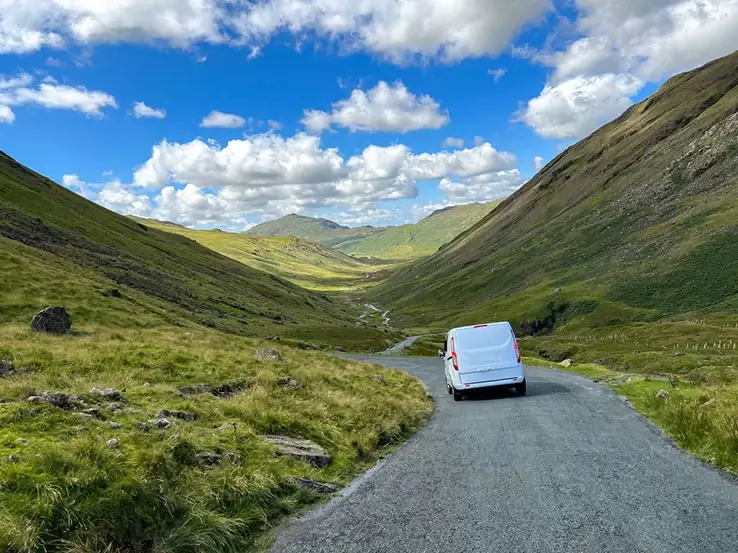 a van driving on a road through the hills