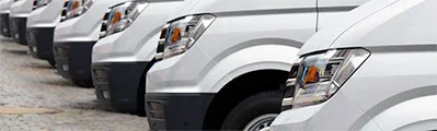 A fleet of white business vans are parked in a row.