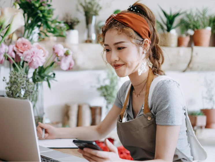 a smiling businesswoman working on her laptop in a flower shop
