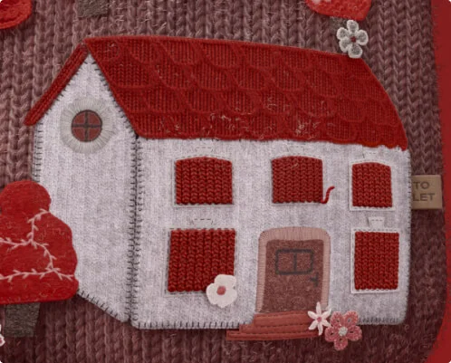 a stitched grey house featuring a red roof and five red windows meant to represent the kind of property a landlord might need to insure.