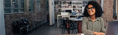 smiling businesswoman sitting at her desk with her laptop