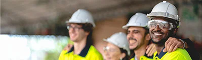 Close-up of four smiling construction workers wearing safety helmets