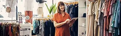 smiling female clothes shop owner using a tablet standing in her shop