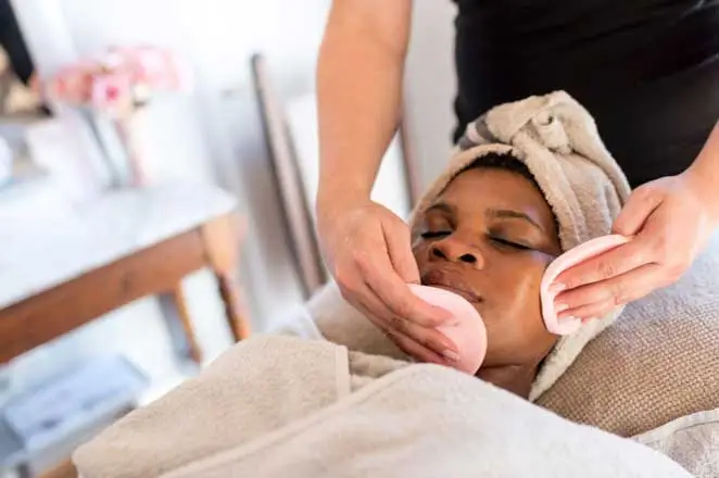 a woman lying back while a beautician gives her a facial